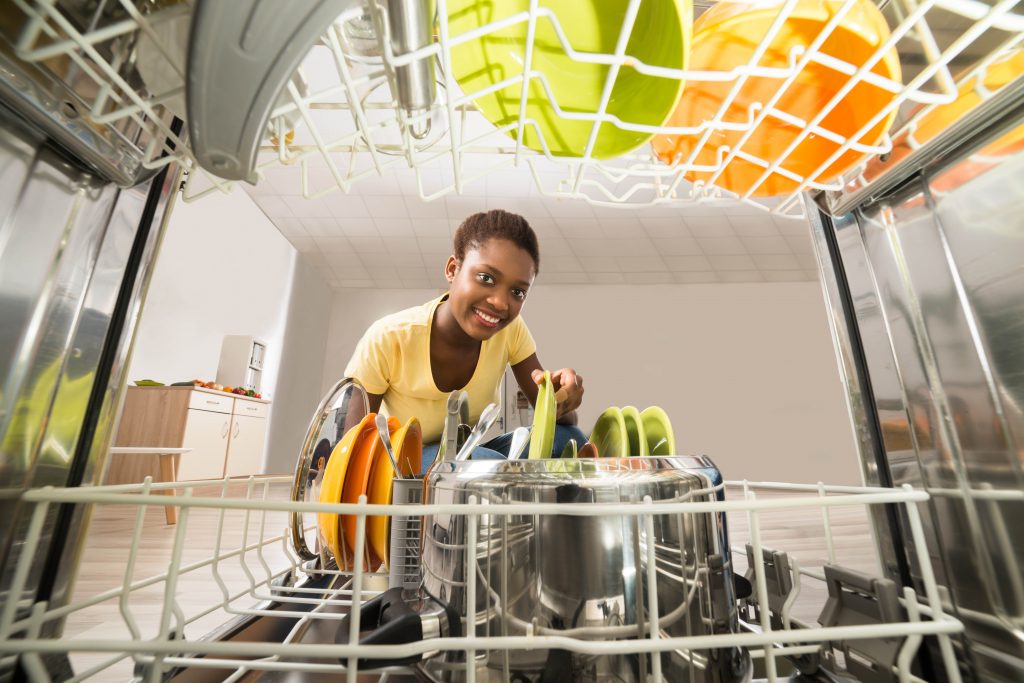 Young Happy African Woman Removing Plate From The Dishwasher